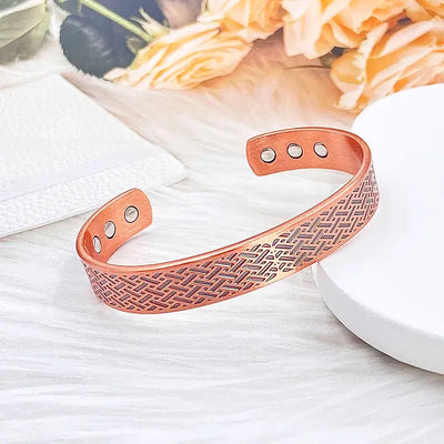 Vintage copper magnetic bracelet displayed on a soft surface with floral accents, ideal for everyday wear.